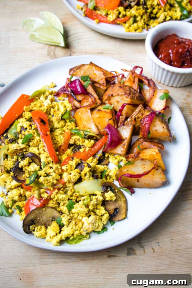 Large white plate filled with veggie tofu scramble and a side of breakfast potatoes.