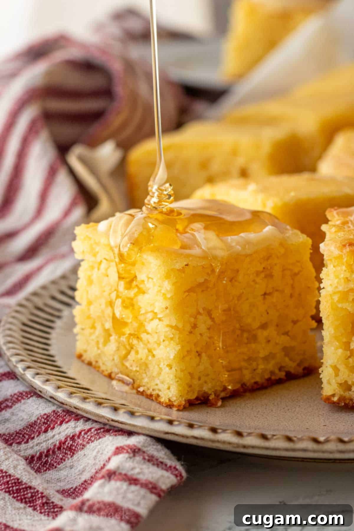 Pouring honey on slice of honey butter cornbread.
