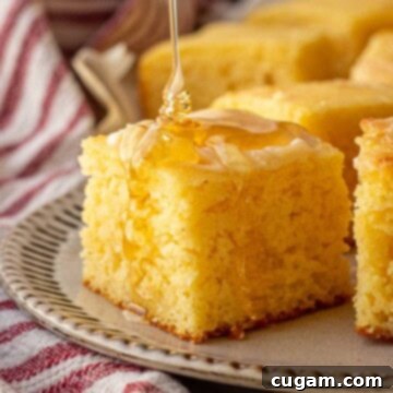 Pouring honey on slice of honey butter cornbread.