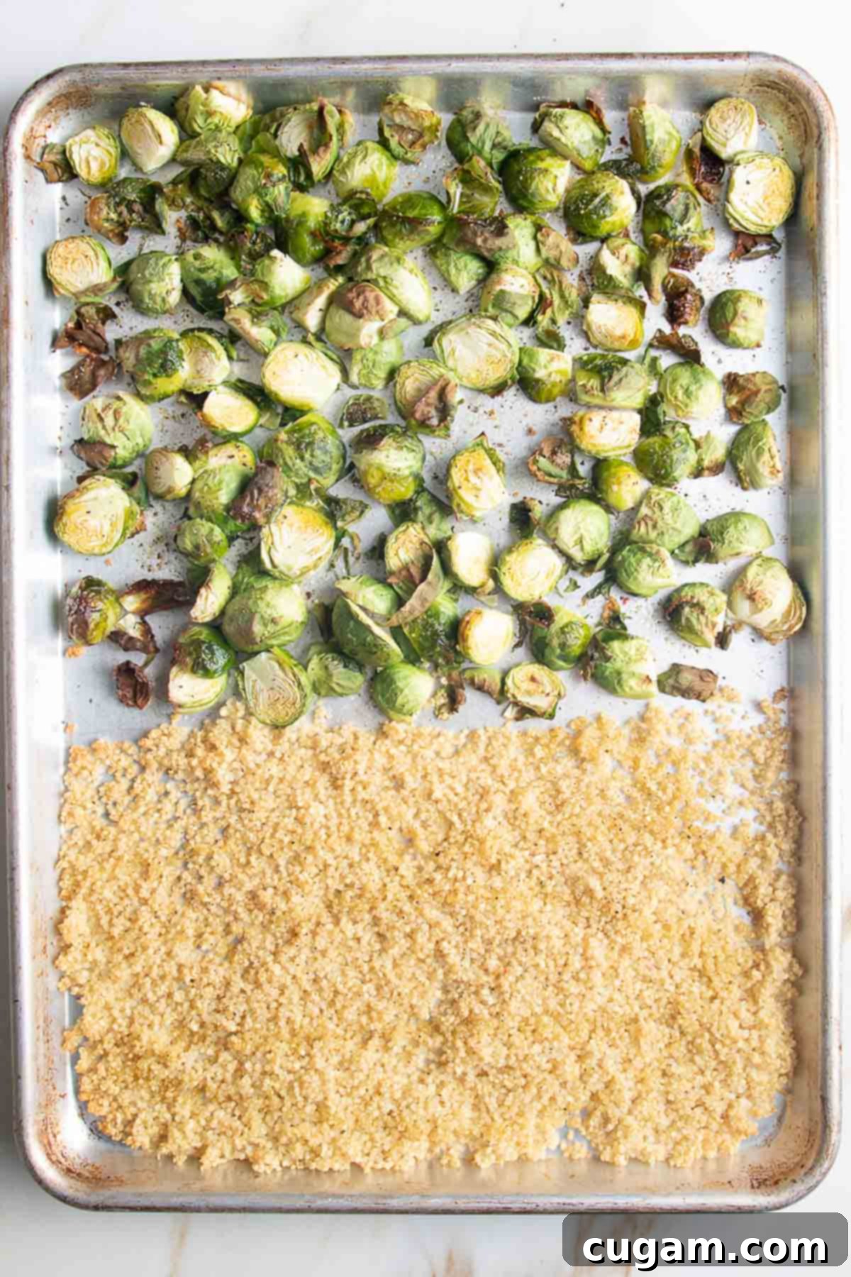 Large baking tray with roasted brussel sprout halves and a pile of crisped quinoa.