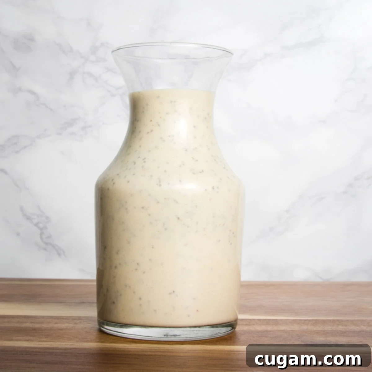 Glass pitcher of creamy salad dressing. 
