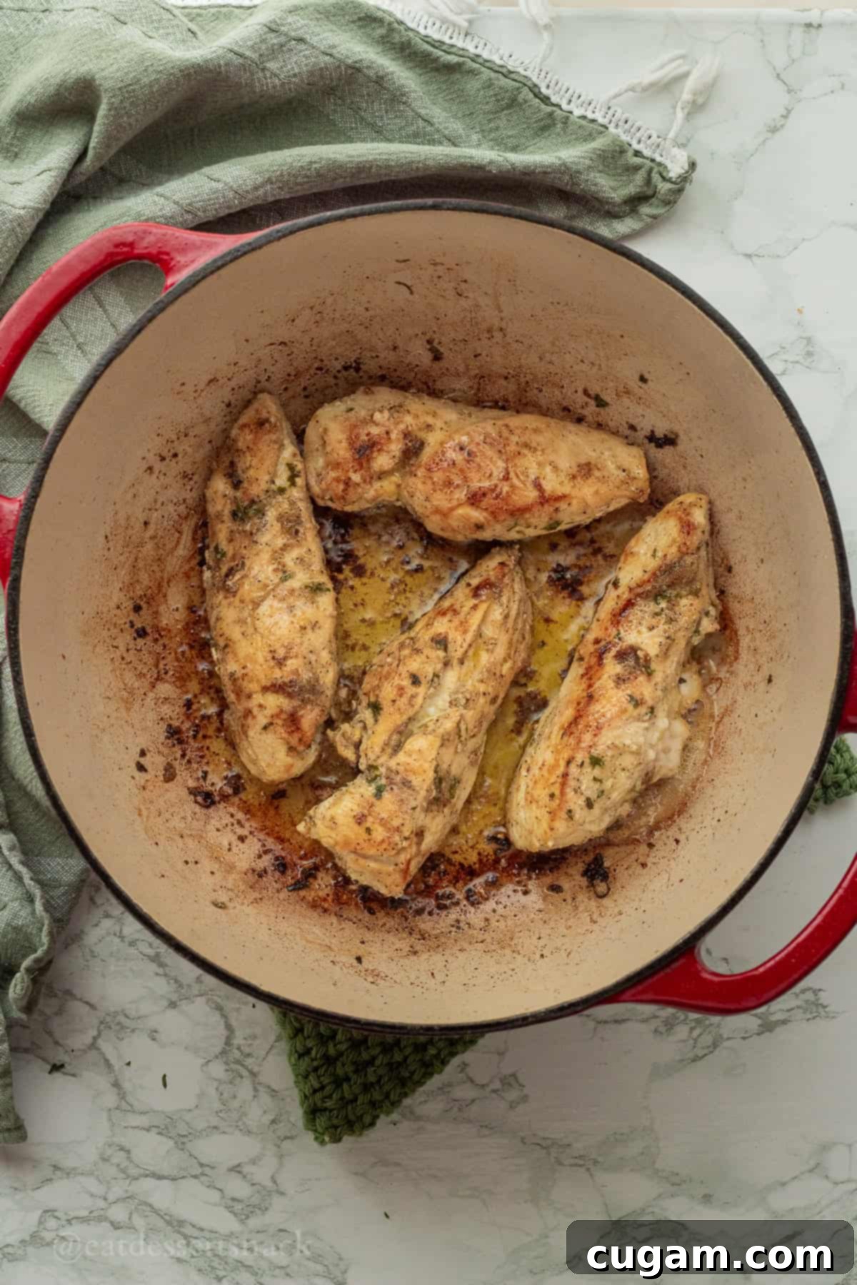 Seared chicken in enameled pan.