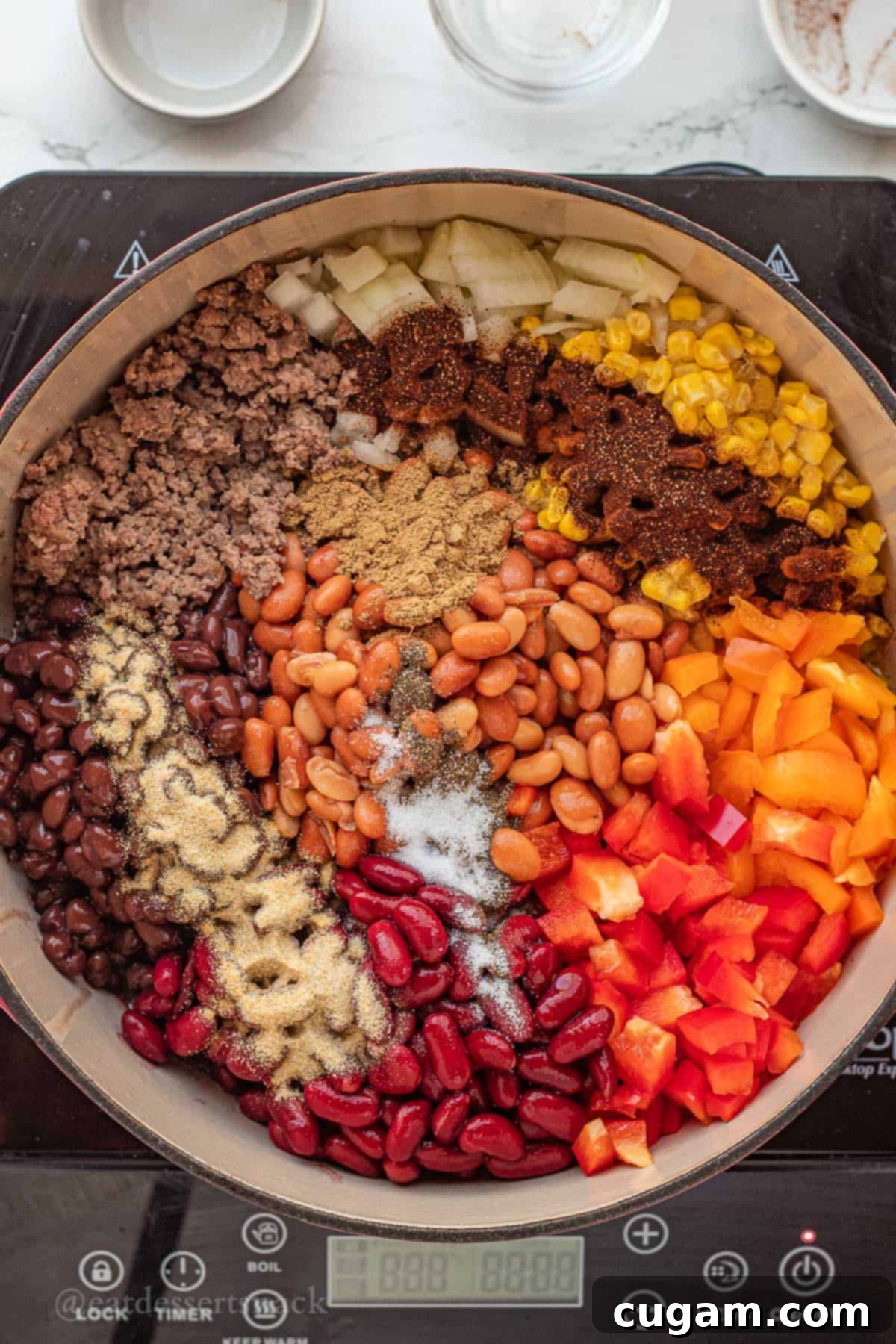 A generous sprinkling of various spices, including chili powder, garlic powder, onion powder, and cumin, layered over the raw ingredients of taco soup in a red pot, adding depth of flavor.
