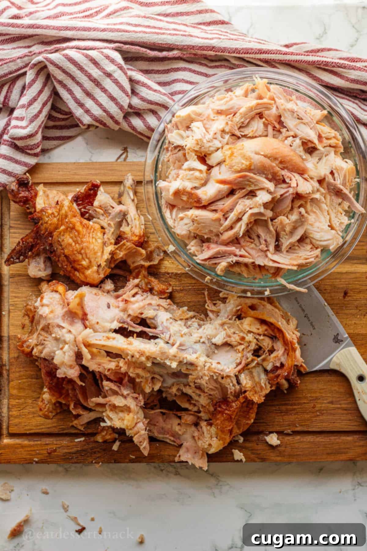 Nourishing Bone Broth Chicken Noodle Soup 4 Removing cooked rotisserie chicken meat from bones on wood cutting board.