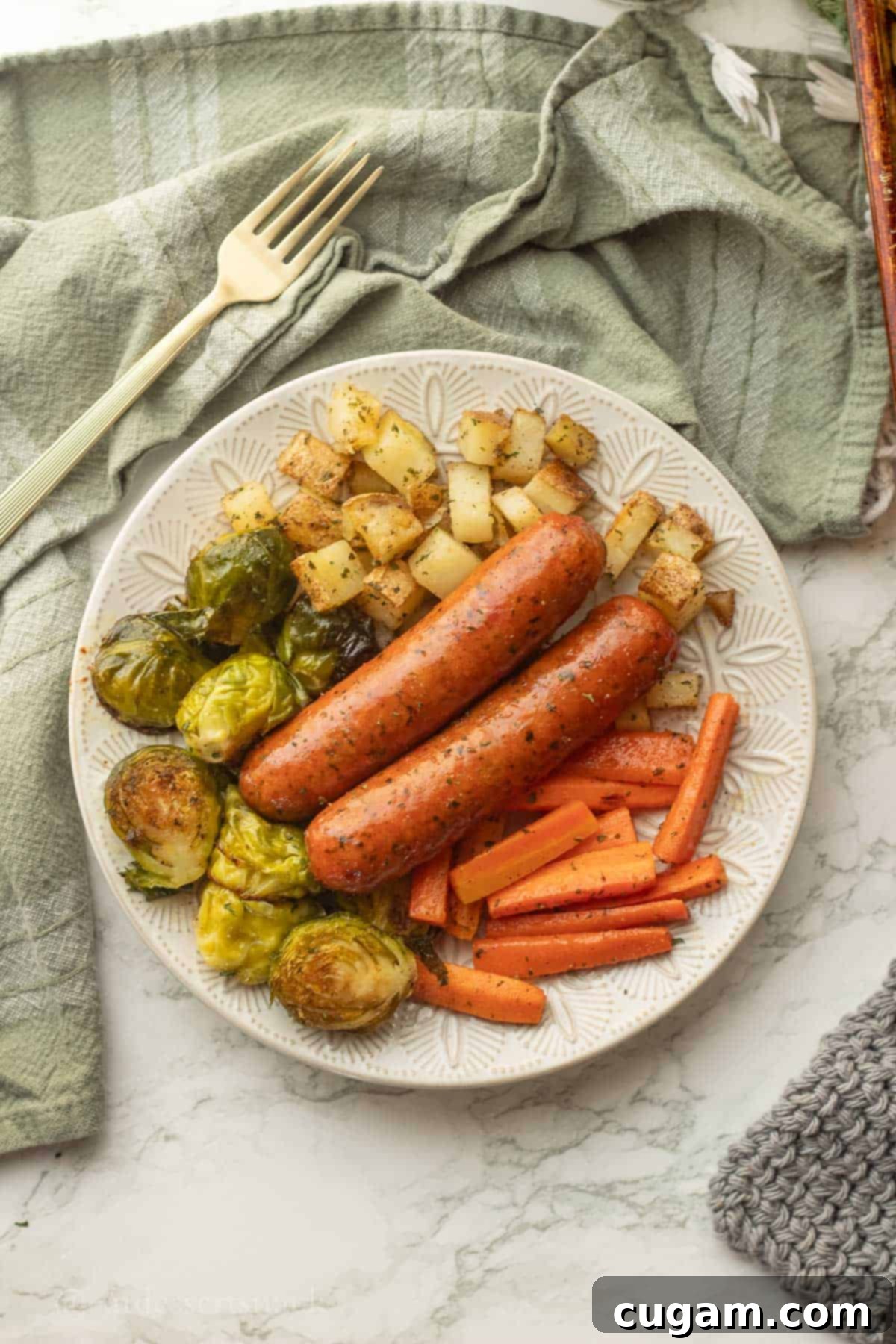 A beautifully plated serving of roasted chicken sausage and mixed vegetables, including potatoes, carrots, and Brussels sprouts, ready to enjoy.