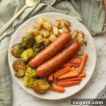A tantalizing close-up of cooked chicken sausage and golden-brown roasted vegetables, perfectly plated and ready to be served.