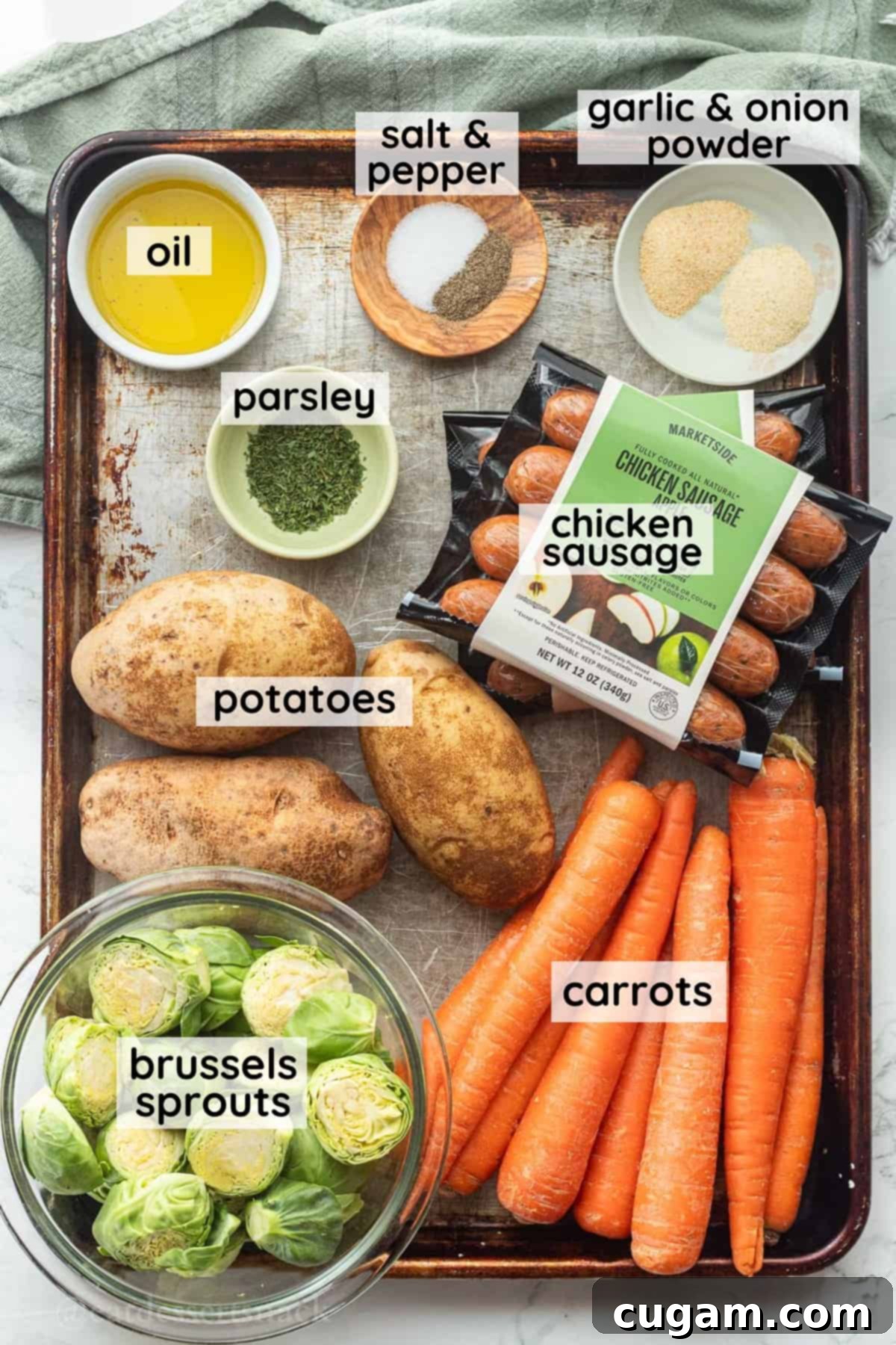 Arrangement of fresh, labeled ingredients for sheet pan chicken sausage and veggies on a metal baking dish, ready for preparation.