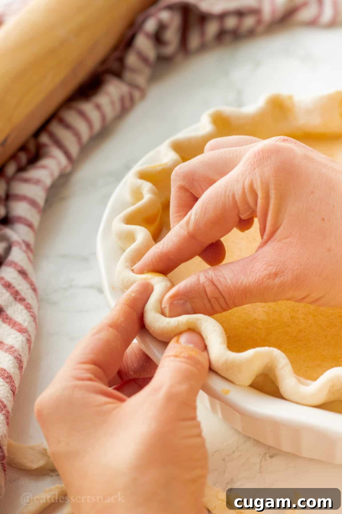 Crimping raw pie crust in pie dish.