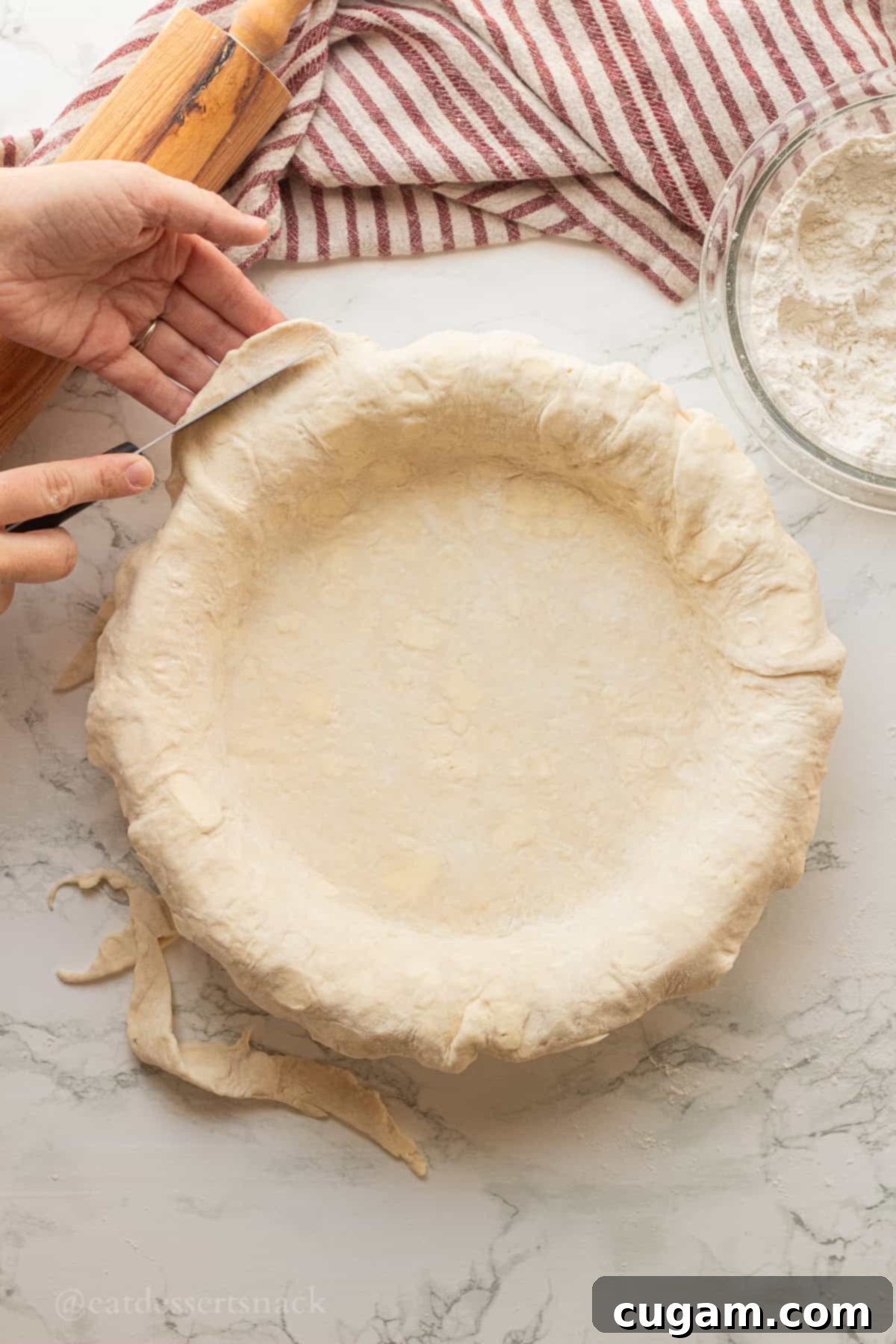 Trimming edges of raw pie dough in ceramic pan.