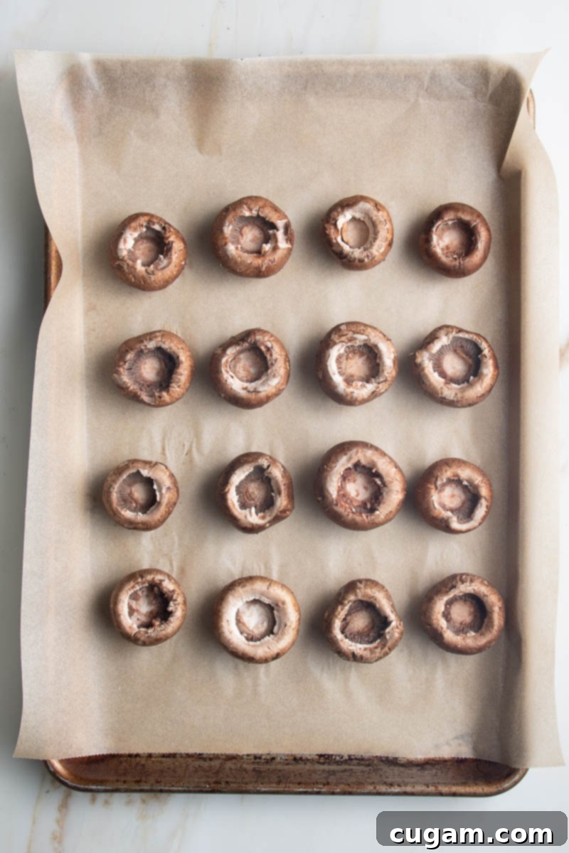 Mushrooms with stems removed on a baking tray lined with parchment. 