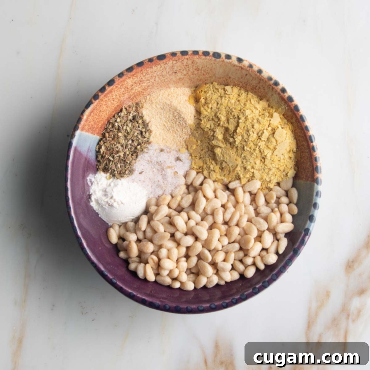Small dish with pine nuts, nutritional yeast, oregano, onion powder, garlic powder.