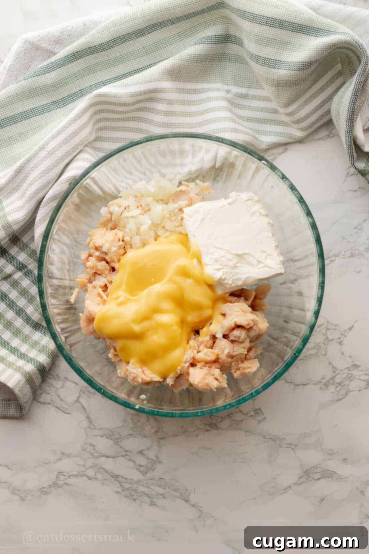 Cream cheese, chicken, onions, and cream of chicken soup in glass bowl.