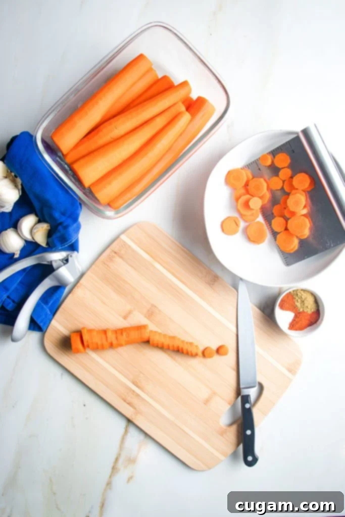 Carrots, whole and sliced, next to bowls of spices and fresh garlic, ready for seasoning.