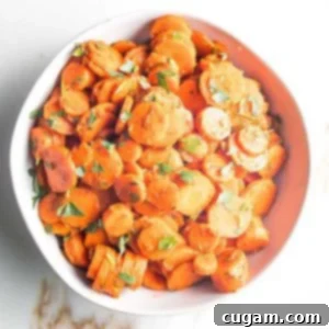 White bowl filled with spiced carrot rounds, sprinkled with chopped green parsley, showcasing the vibrant Moroccan Carrots.
