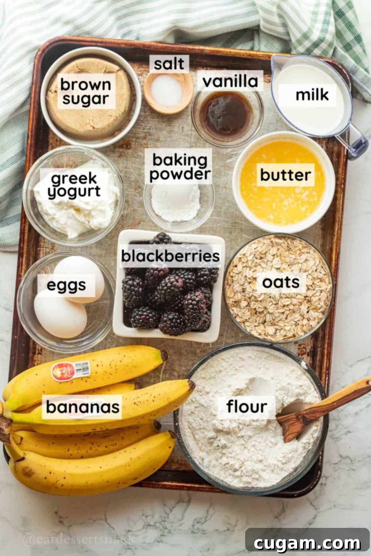 Labeled ingredients for banana blackberry oat muffins on metal baking sheet.