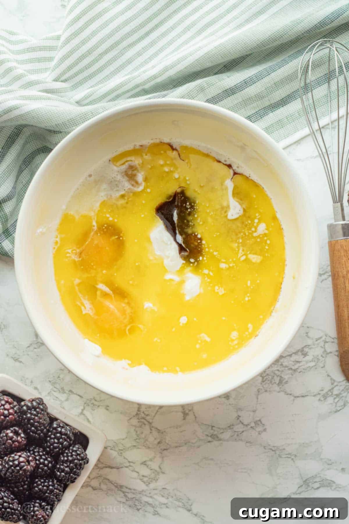 Eggs, butter, vanilla, bananas, milk, and greek yogurt in white bowl.