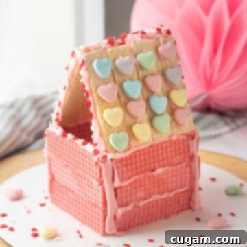 Pink wafer cookie house with hearts on roof.