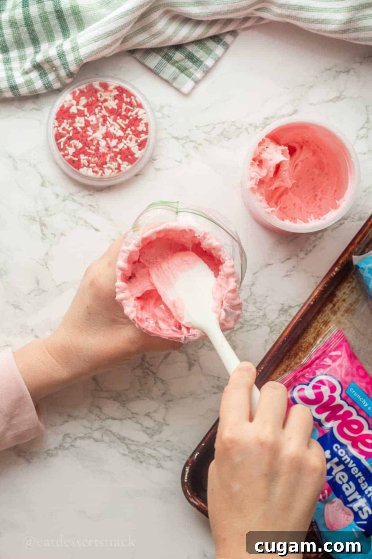 Spatula spreading pink frosting into a piping bag.