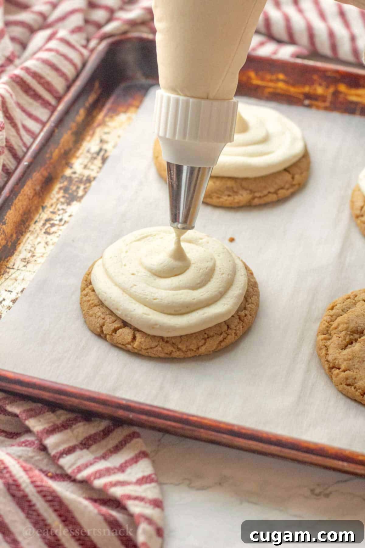 Piping frosting cheesecake frosting on graham cracker cookie.