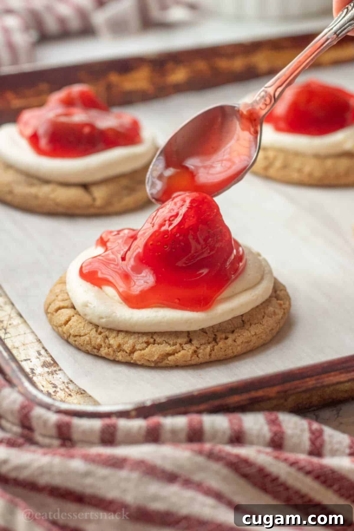 Spoon with strawberry pie filling above baked graham cracker cookie.