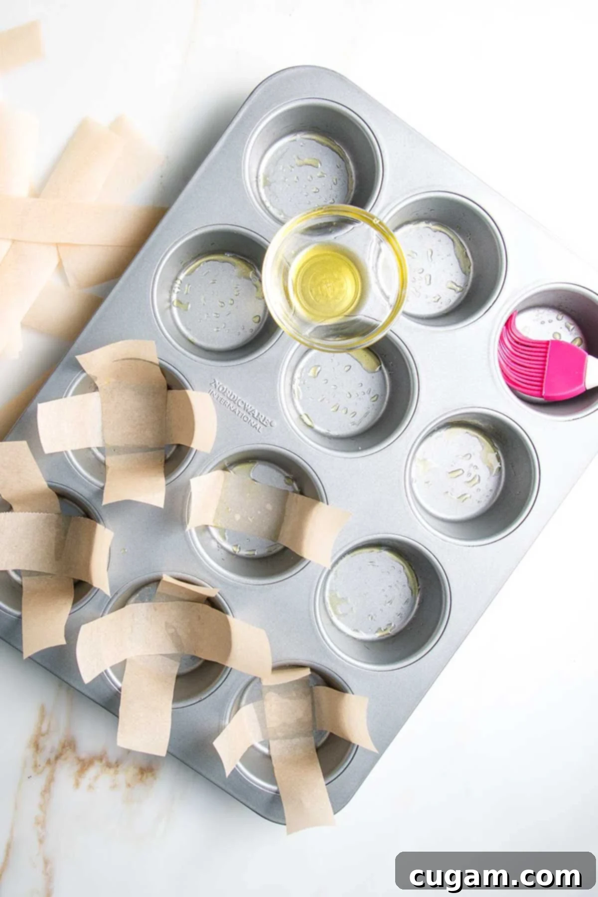 Muffin tin, neatly brushed with oil and lined with criss-crossed strips of unbleached parchment paper, ready for batter.
