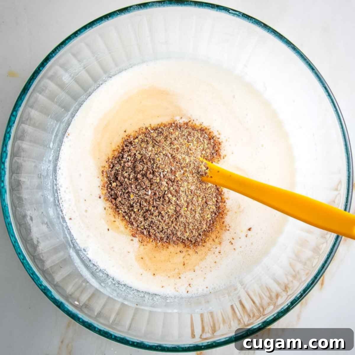 Stirring ground flax seeds into the wet mixture, letting it sit to thicken.