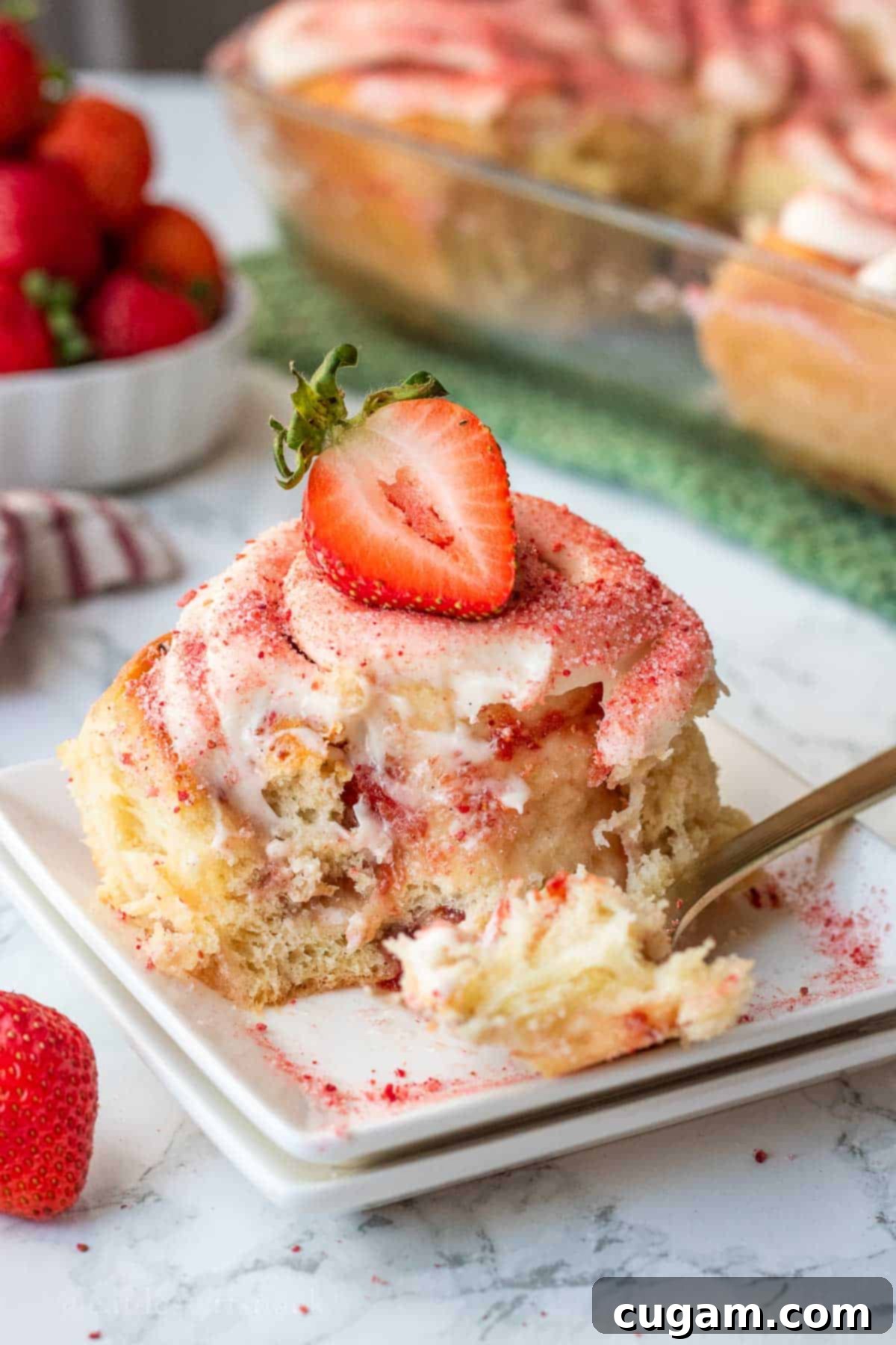 Baked strawberry roll on white plate with bite removed.