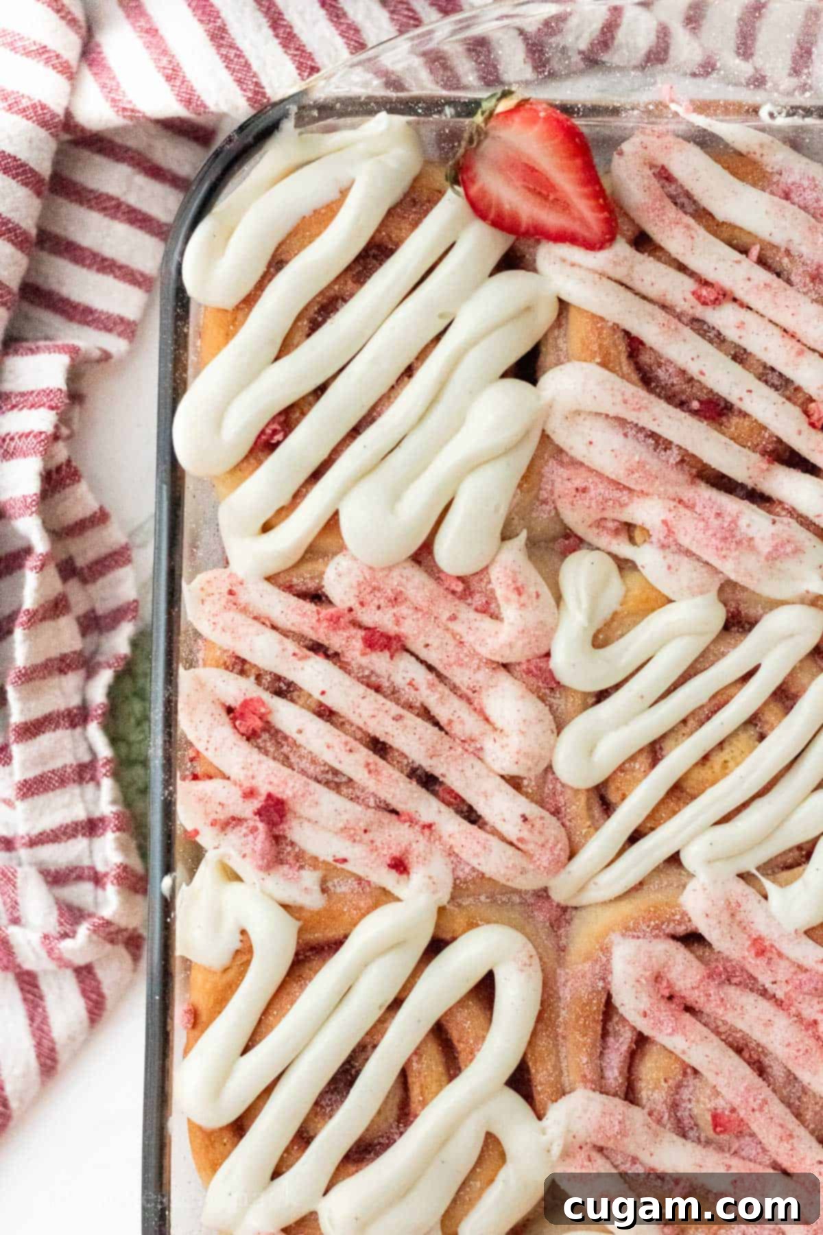 Baked strawberry cheesecake cinnamon rolls in glass pan.