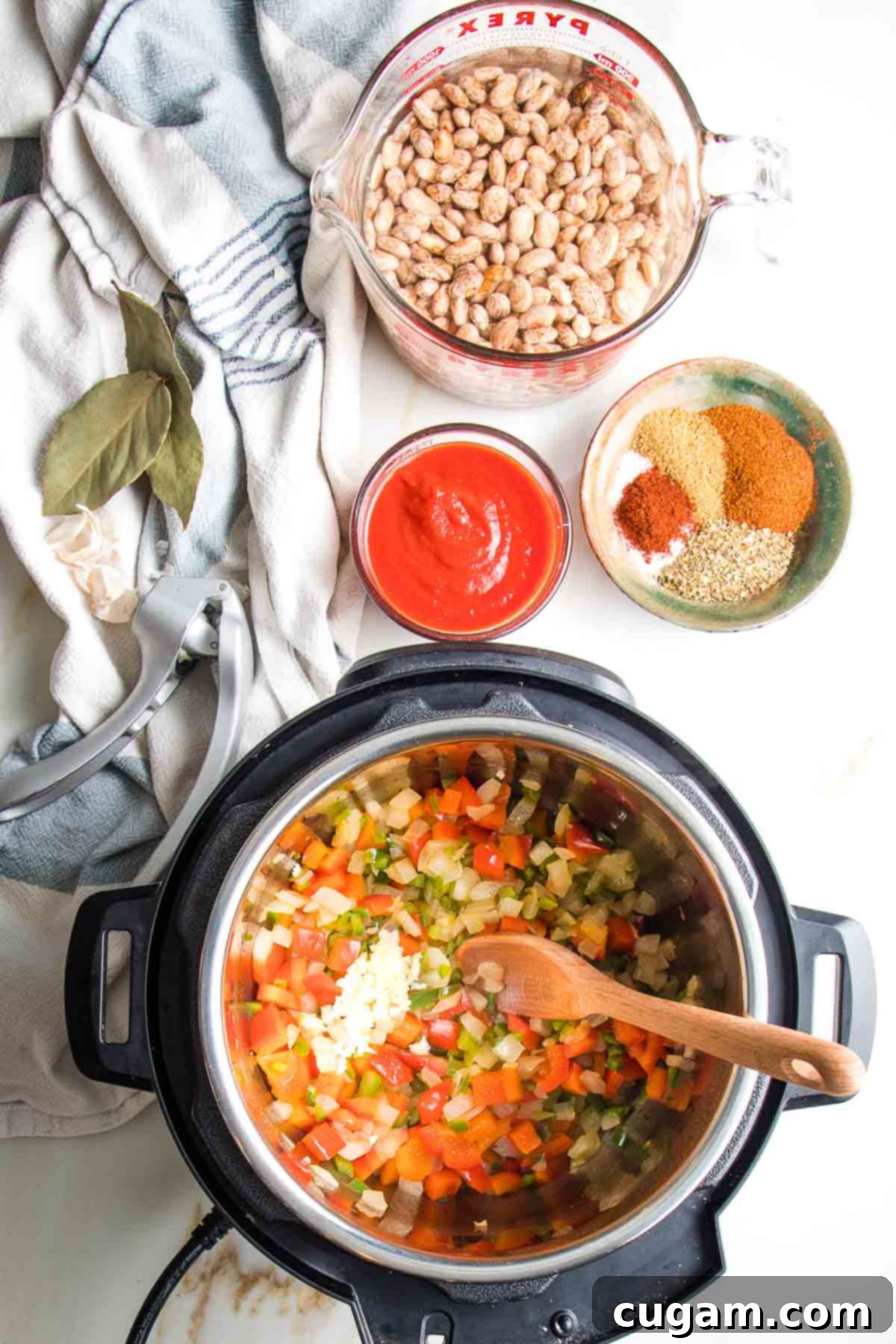 Instant pot with sauteed veggies, pressed garlic on top. Also some tomato sauce, spices and soaking pinto beans.