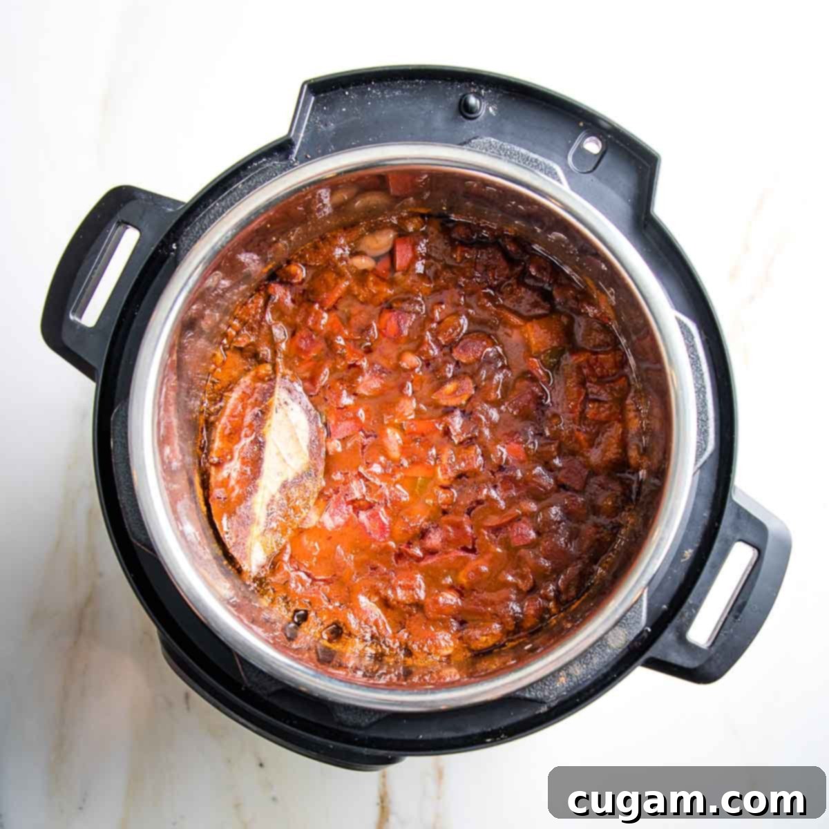 Instant pot with cooked beans in tomato sauce with veggies.