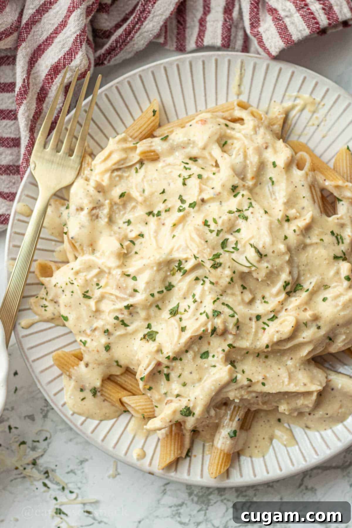 Cooked crockpot italian chicken on white plate with gold fork.