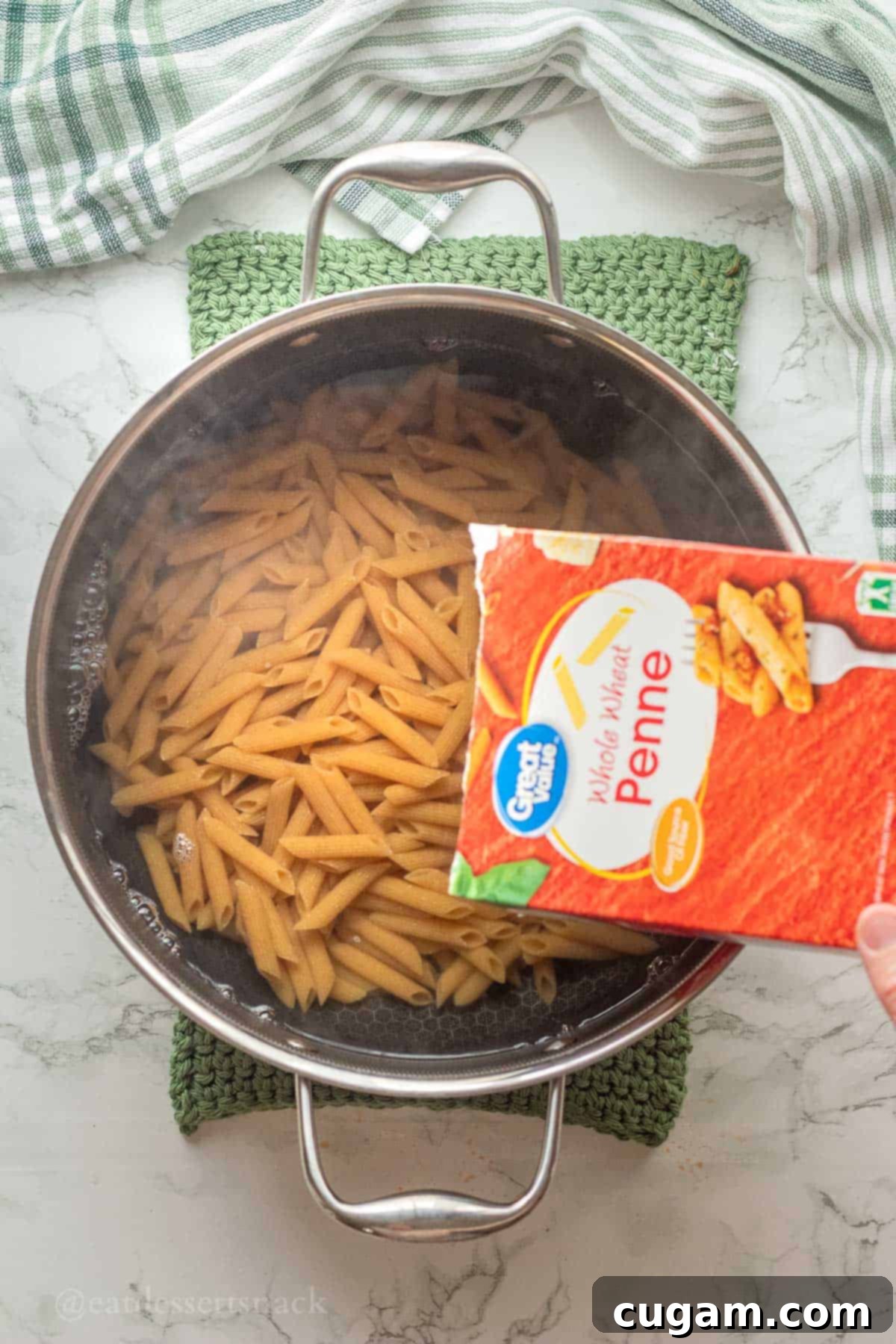 Pouring uncooked pasta into pot of water.