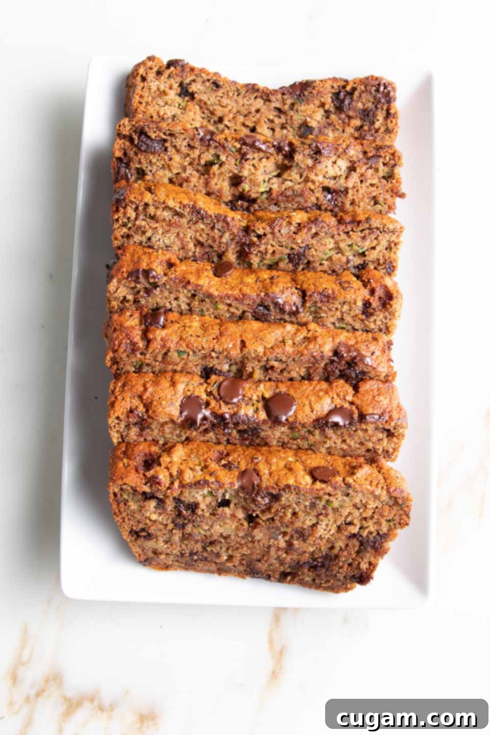 Slices of healthy chocolate chip zucchini bread on a white platter, showcasing its moist texture.