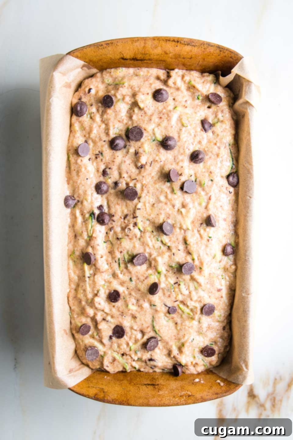 Zucchini bread with chocolate chips in a loaf pan, waiting to be baked.