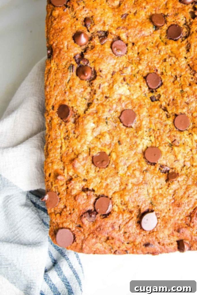 A loaf of healthy and moist zucchini bread with chocolate chips cooling on a cotton tea towel.