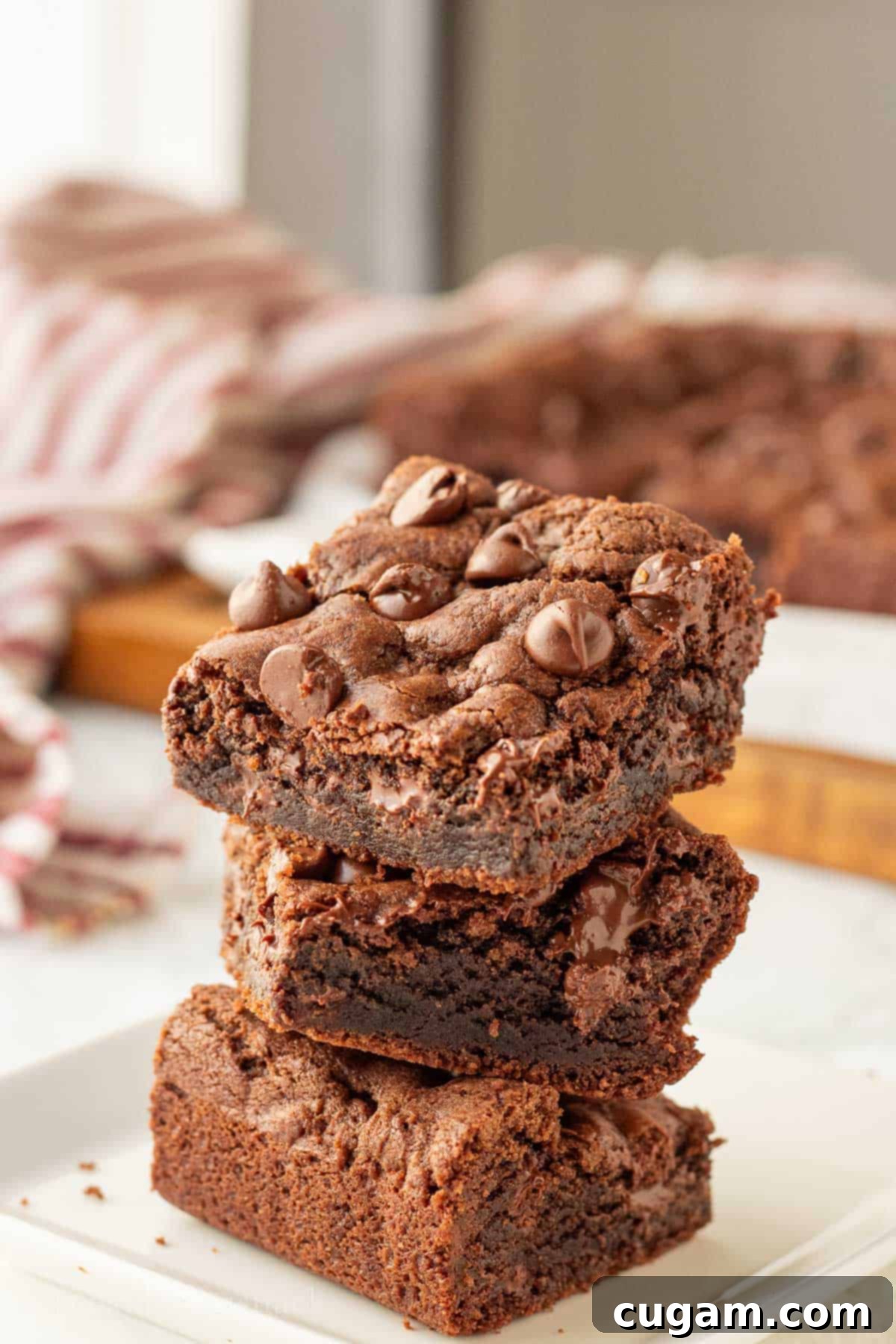 Stack of baked chocolate chocolate chip cookie bars on white plate.