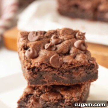 Stack of baked chocolate chocolate chip cookie bars on white plate.