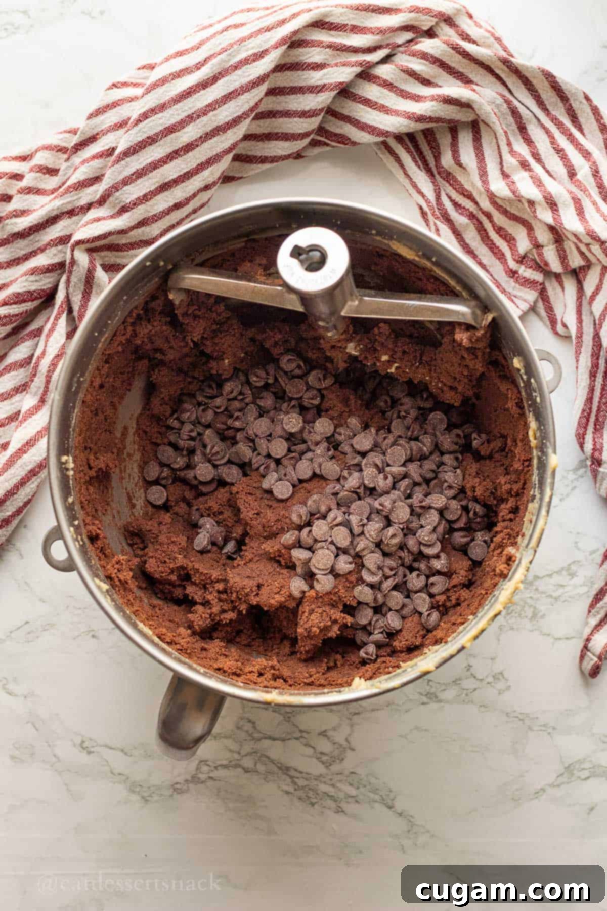 Chocolate chips in raw double chocolate chip cookie batter in metal mixing bowl.