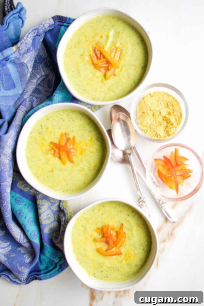 Easy Creamy Zucchini Soup 2 Creamy green soup in bowls with red pepper garnish.