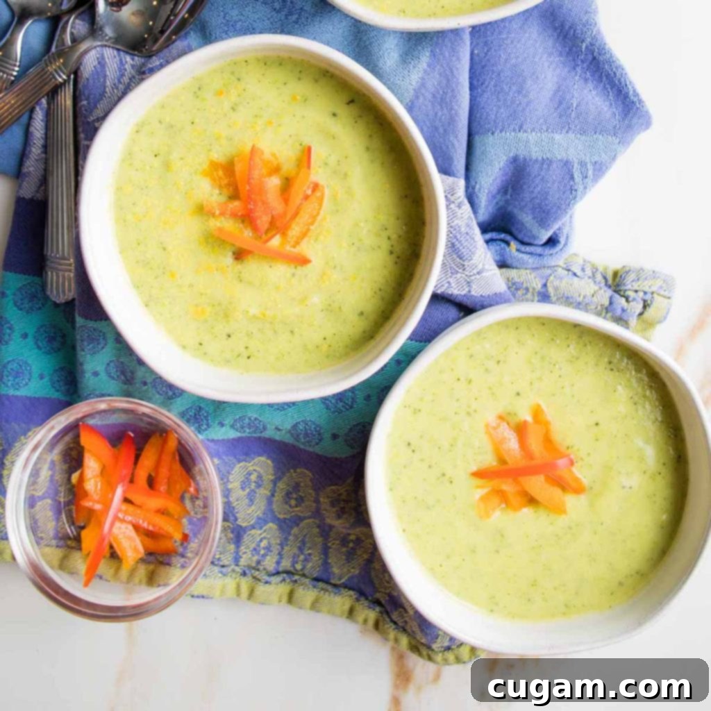Easy Creamy Zucchini Soup 11 Two bowls of creamy green soup, garnished with julienned red pepper slices.