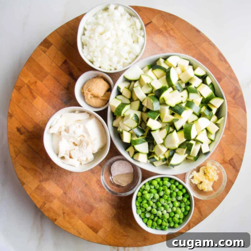 Easy Creamy Zucchini Soup 5 Prepped ingredients like chopped zucchini, peas, garlic, chopped onions, miso paste for creamy zucchini soup.