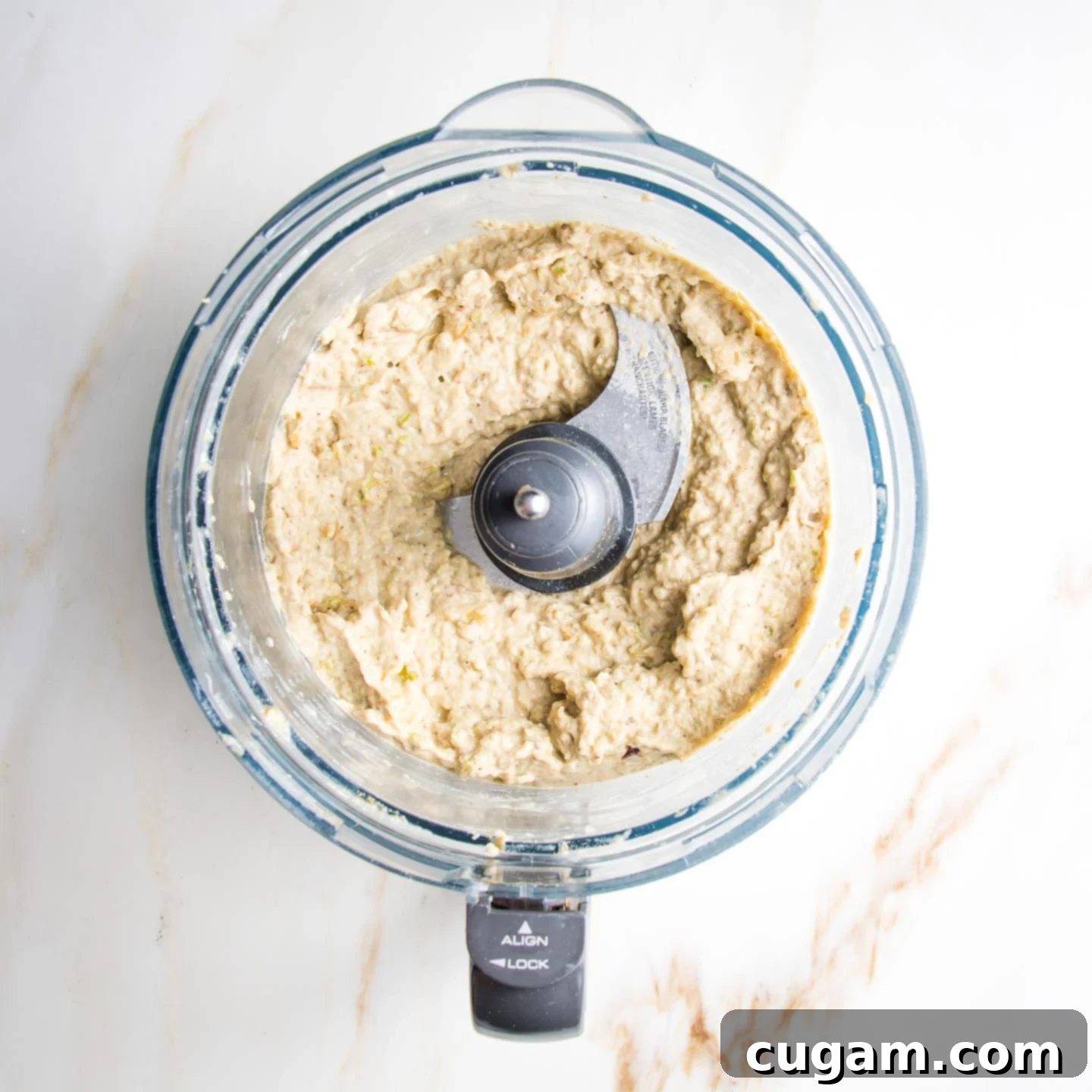 Beige, creamy dip, with some texture, in the bowl of a food processor.