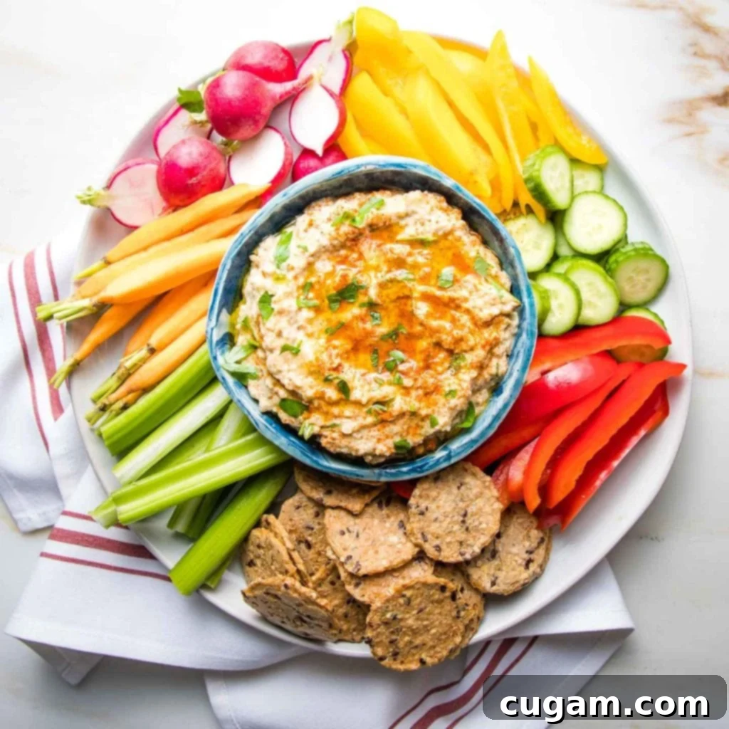 Colorful Crudites with a bowl of roasted eggplant dip in the center that is garnished with paprika and fresh parsley