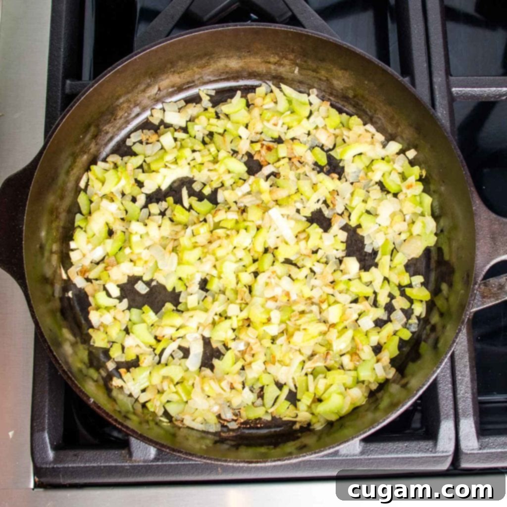 Cast iron skillet with sauteed onions and celery that are caramelized.