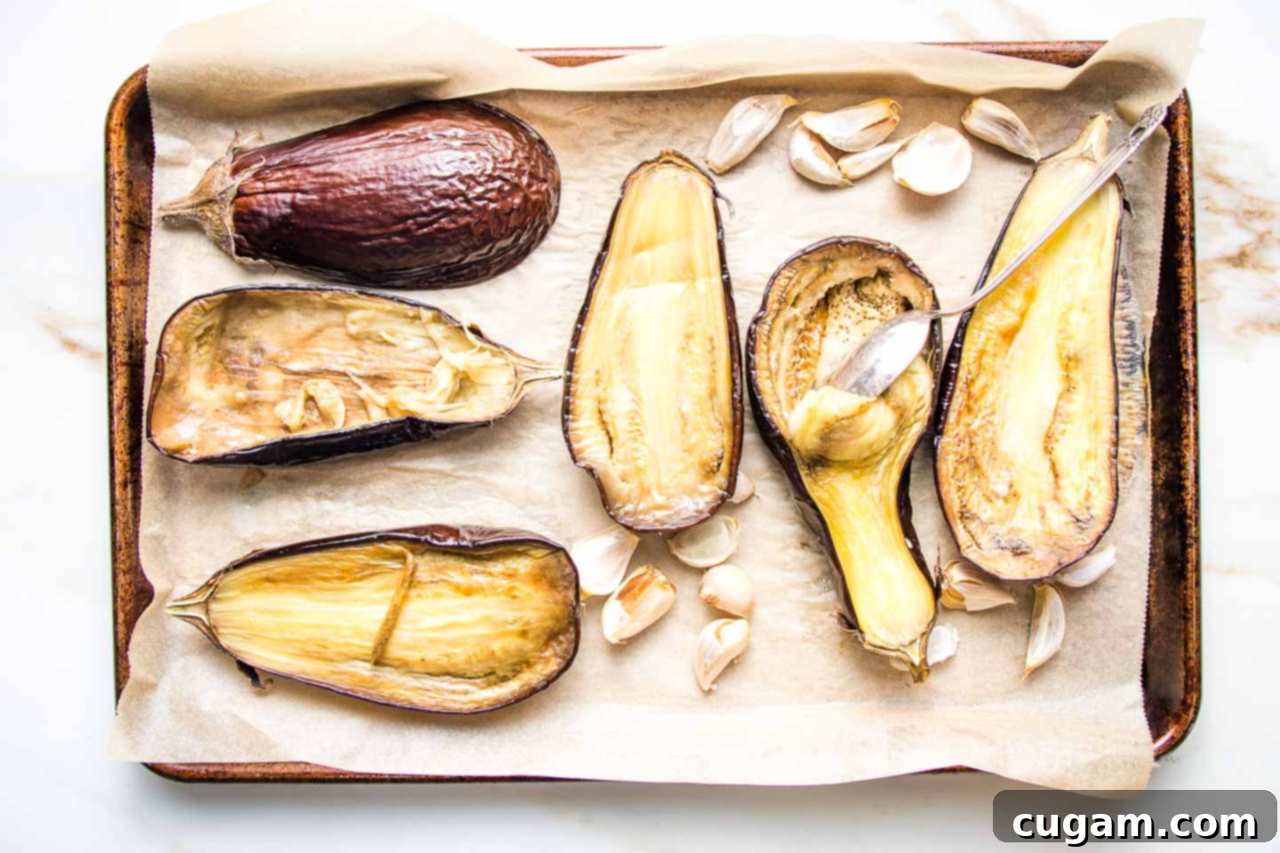 Scooping out the pulp of roasted eggplant with a spoon.