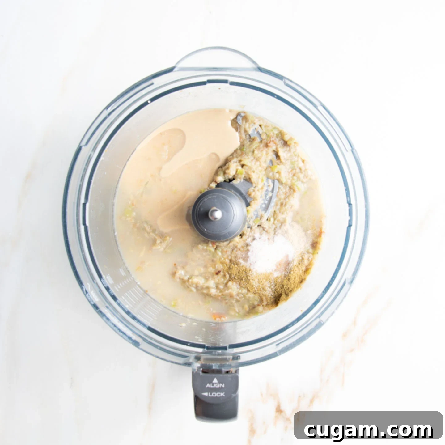 Tahini, lemon juice and spices added to some eggplant dip in a food processor.
