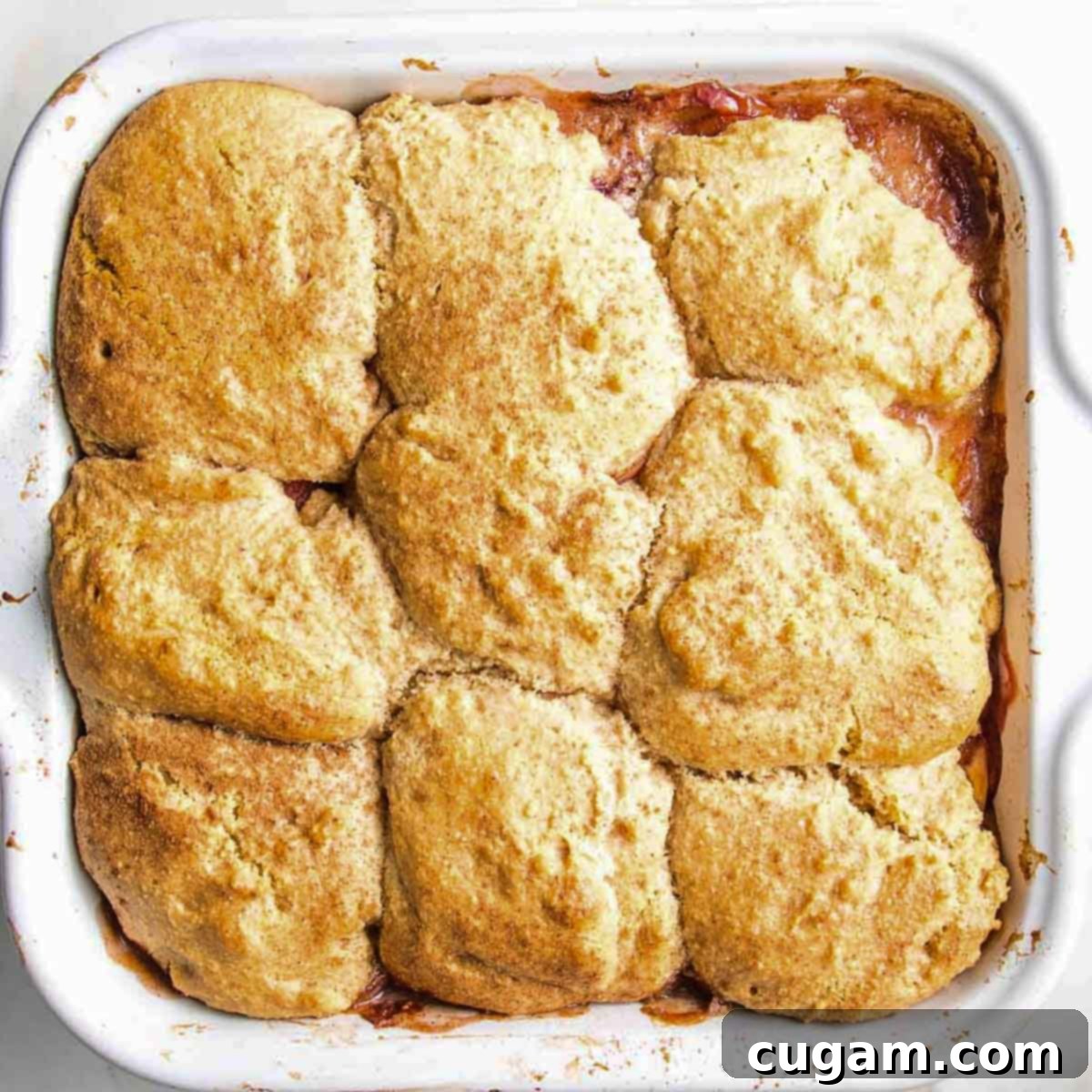 A square baking dish of uncooked peach cobbler, ready for the oven.