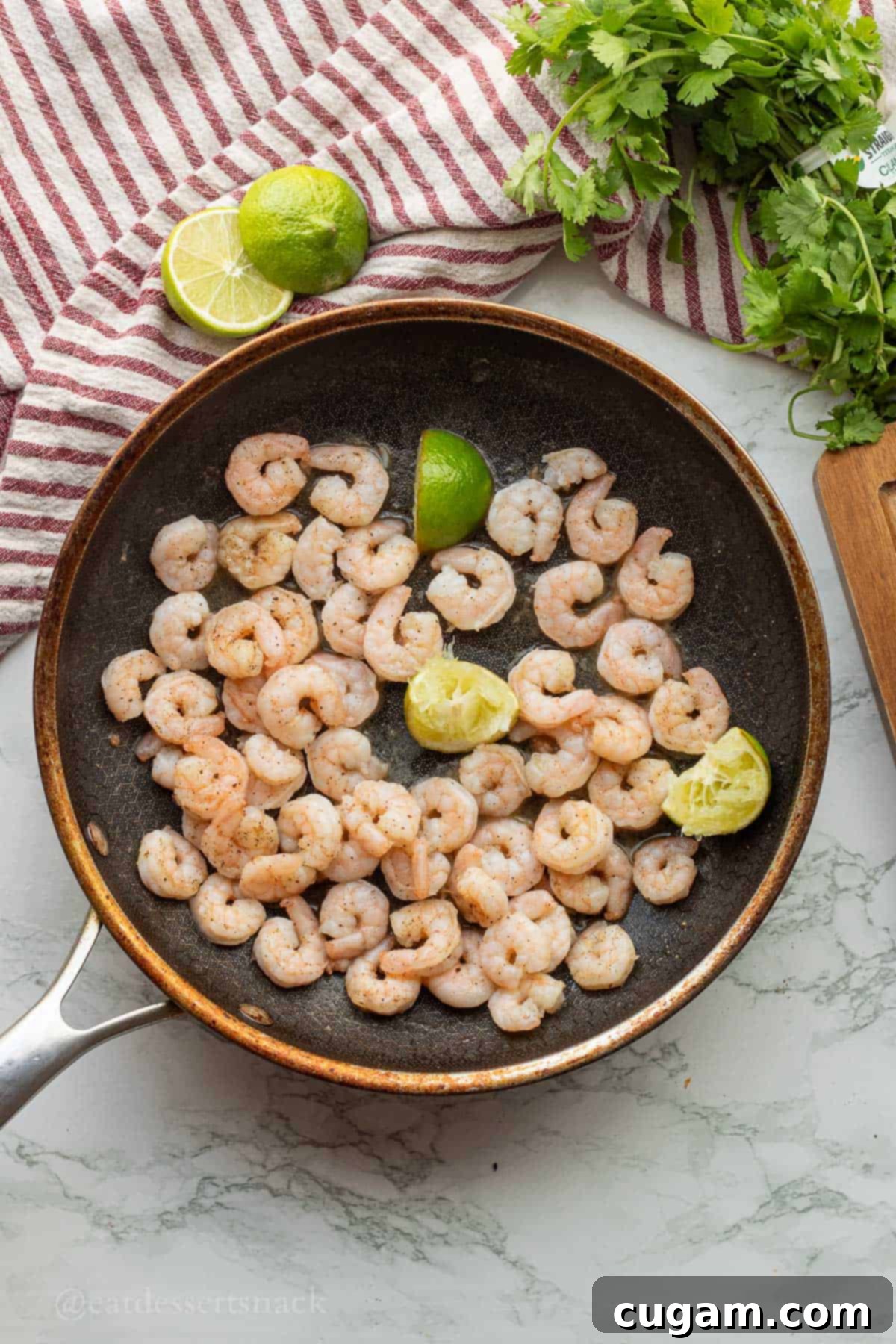 Cooked shrimp with lime in frying pan.