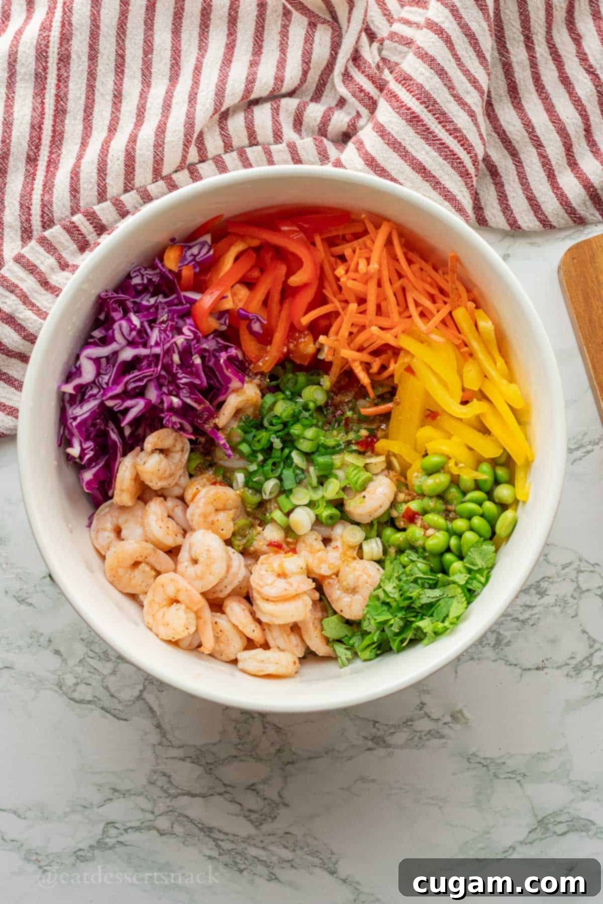 Rainbow veggies in white bowl with shrimp.