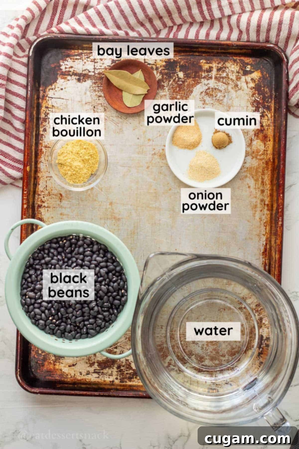 Labeled ingredients for instant pot black beans in glass bowls on metal baking sheet.